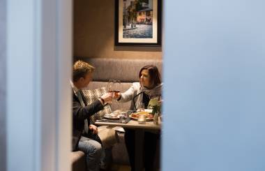 Pärchen stoßen mit Weinglas beim Dinner an