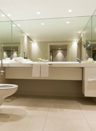 Hotel-Badezimmer mit Spiegelwand und modernen Waschbecken